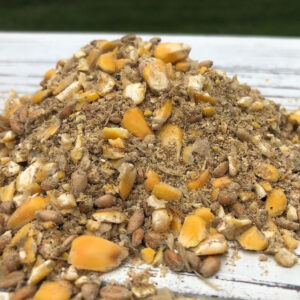 Pile of crushed mixed nuts and small dried fruit pieces on a white wooden surface.