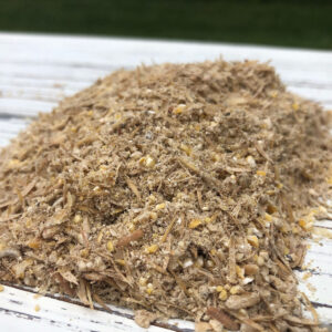 Pile of wood shavings and sawdust on a white wooden surface outdoors.
